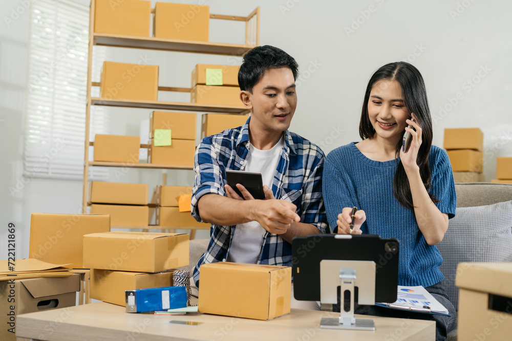 couple start up small business owner writing address on cardboard box at workplace.small business entrepreneur SME or freelance asian couple working with box at home. couple start up small business owner writing address on cardboard box at workplace.small business entrepreneur SME or freelance asian couple working with box at home.
