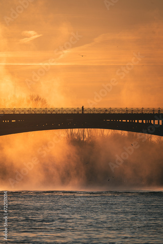 Mann auf Brücke bei Sonnenaufgang über Fluss