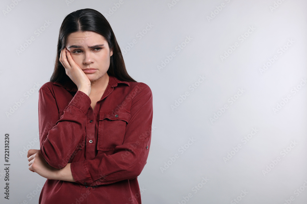 Sadness. Unhappy woman in red shirt on gray background, space for text Sadness. Unhappy woman in red shirt on gray background, space for text