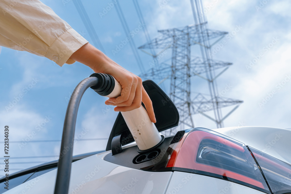 Closeup woman recharge EV electric car battery at charging station