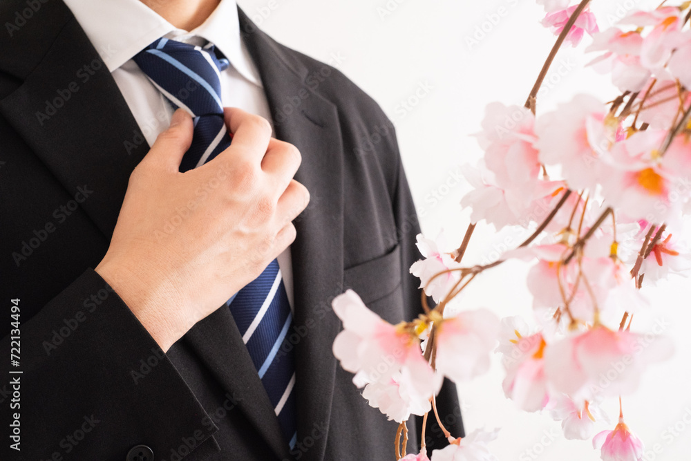 スーツ男性と桜で新入社員のイメージ