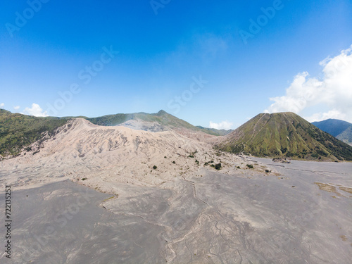 Aerial view of a vast volcanic landscape with ash-covered ground and craters.