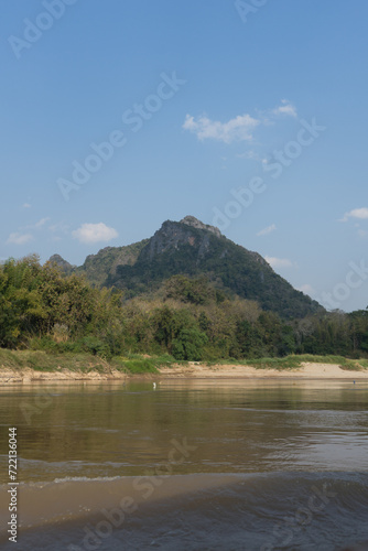 A tranquil river scene with a mountain backdrop under a clear sky.