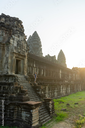 Konstfotografi Person standing on the ancient steps of a majestic Angkor Wat temple at dusk