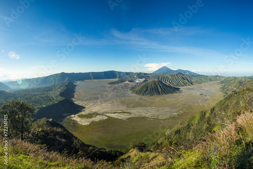 Obraz na płótnie Panoramic view of a vast volcanic landscape with verdant hills under a clear blue sky