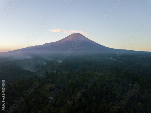 A tranquil early morning view of a majestic volcano rising above a forest