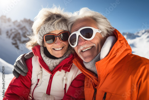 Happy senior couple in winterwear standing on top of a snowy mountain