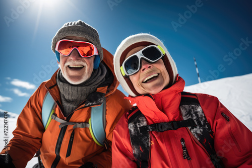 Happy senior couple in winterwear standing on top of a snowy mountain