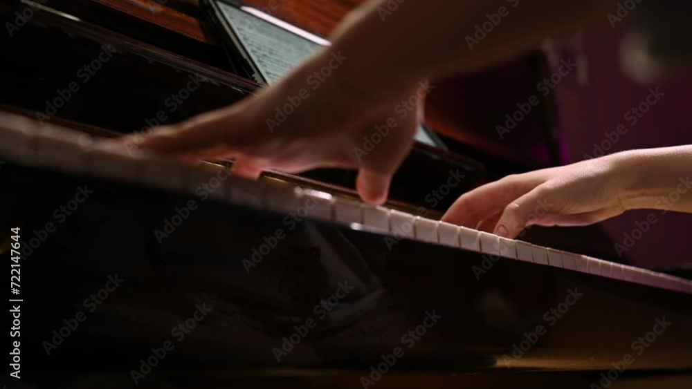 Bottom view of the hands of a young woman playing the piano.