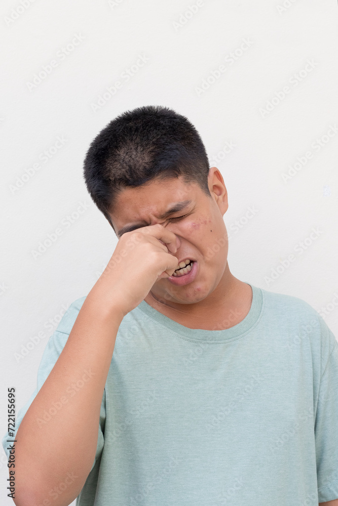 Close up face of teenage guy, hands on the nose, smelly stinky face expression. Close up face of teenage guy, hands on the nose, smelly stinky face expression.