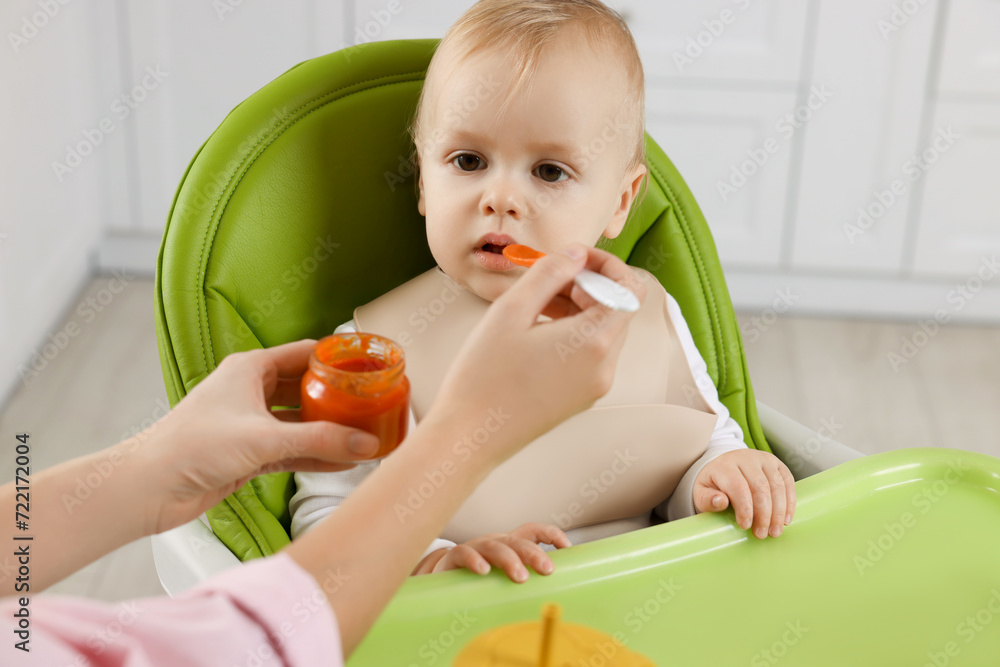 Mother feeding her cute little baby with healthy food at home Mother feeding her cute little baby with healthy food at home