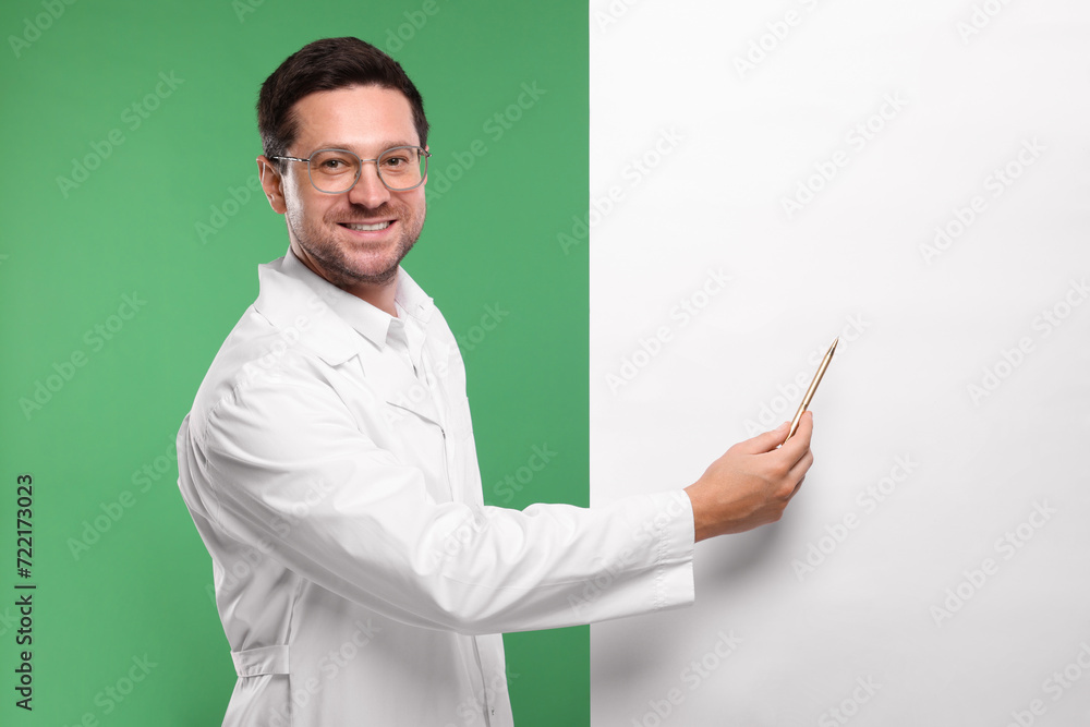Ophthalmologist pointing at blank banner on green background, space for text Ophthalmologist pointing at blank banner on green background, space for text