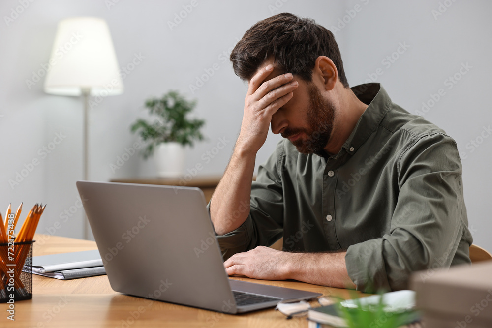 Tired man suffering from headache at workplace Tired man suffering from headache at workplace