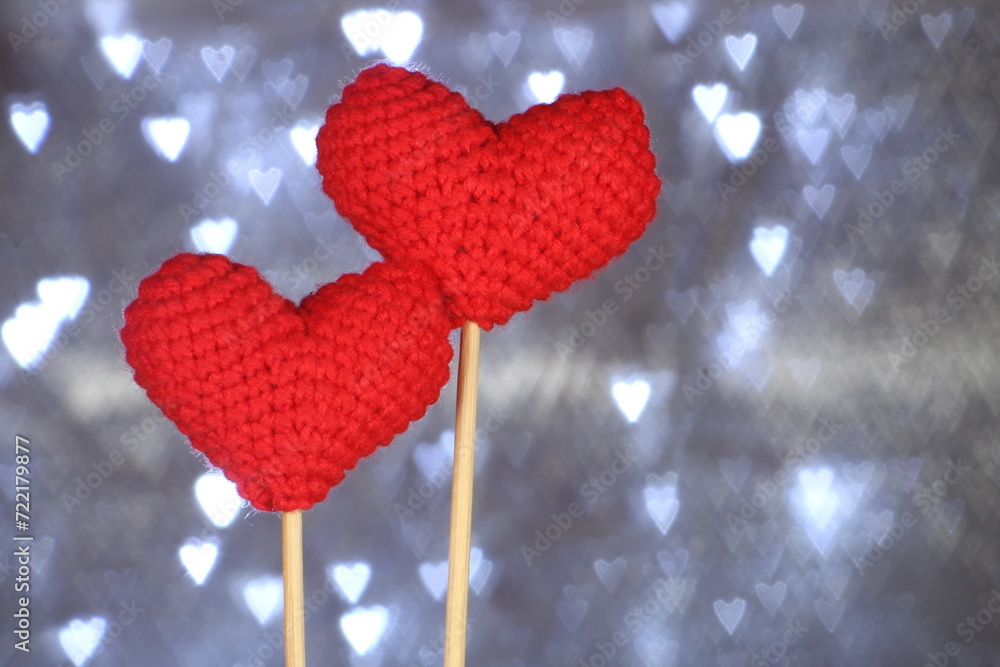 Fototapeta premium Valentine day concept idea. Two knitted red heart. Heart shaped bokeh on background. Selective focus. 