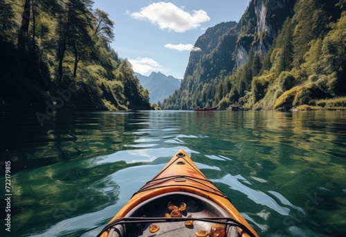 A lone sea kayak glides peacefully along a serene river, surrounded by majestic mountains and lush trees, as the clear blue sky and gentle watercourse transport the paddler on an adventurous outdoor  © Martin