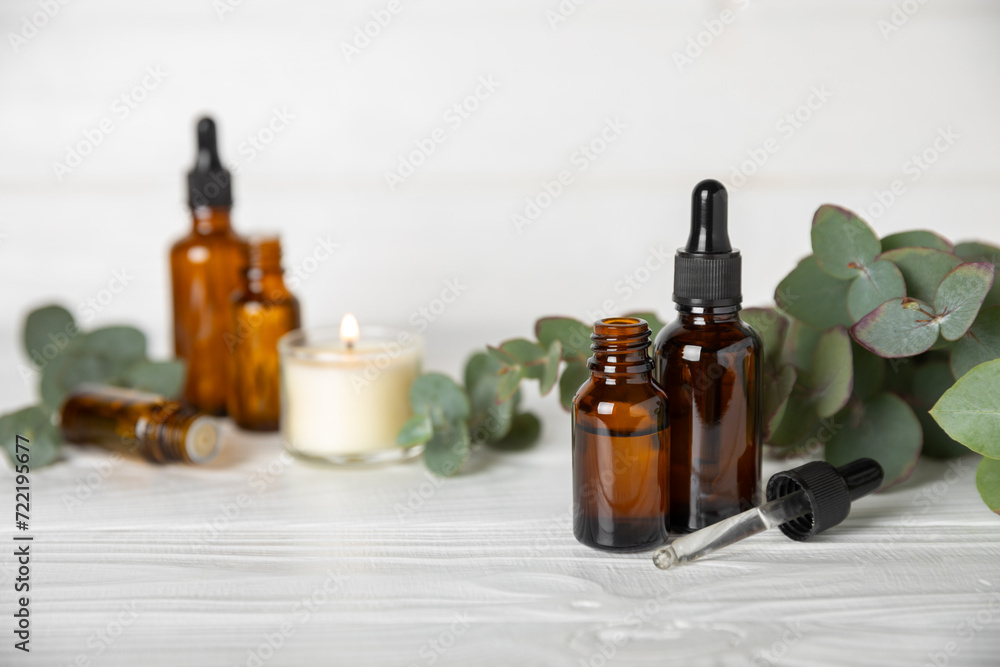 Eucalyptus essential oil in a glass bottle with green eucalyptus leaves on a textured wooden background. Aromatherapy concept. Spa. Natural organic ingredients for cosmetics and body care.Copy space Eucalyptus essential oil in a glass bottle with green eucalyptus leaves on a textured wooden background. Aromatherapy concept. Spa. Natural organic ingredients for cosmetics and body care.Copy space