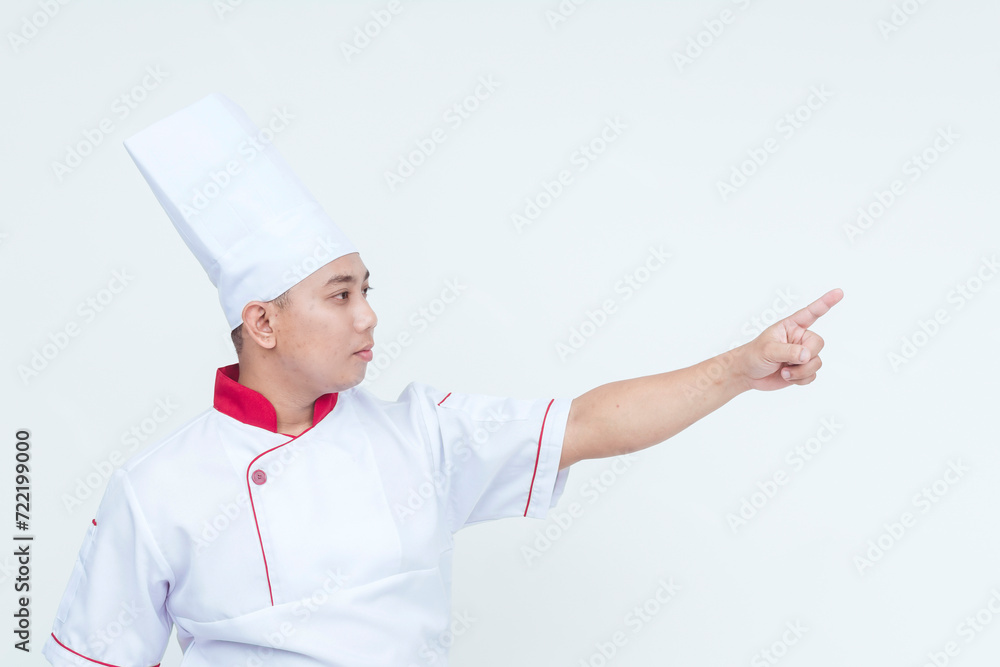 Professional Asian male chef in traditional uniform pointing to the side on a clean white background, with copy space. Professional Asian male chef in traditional uniform pointing to the side on a clean white background, with copy space.