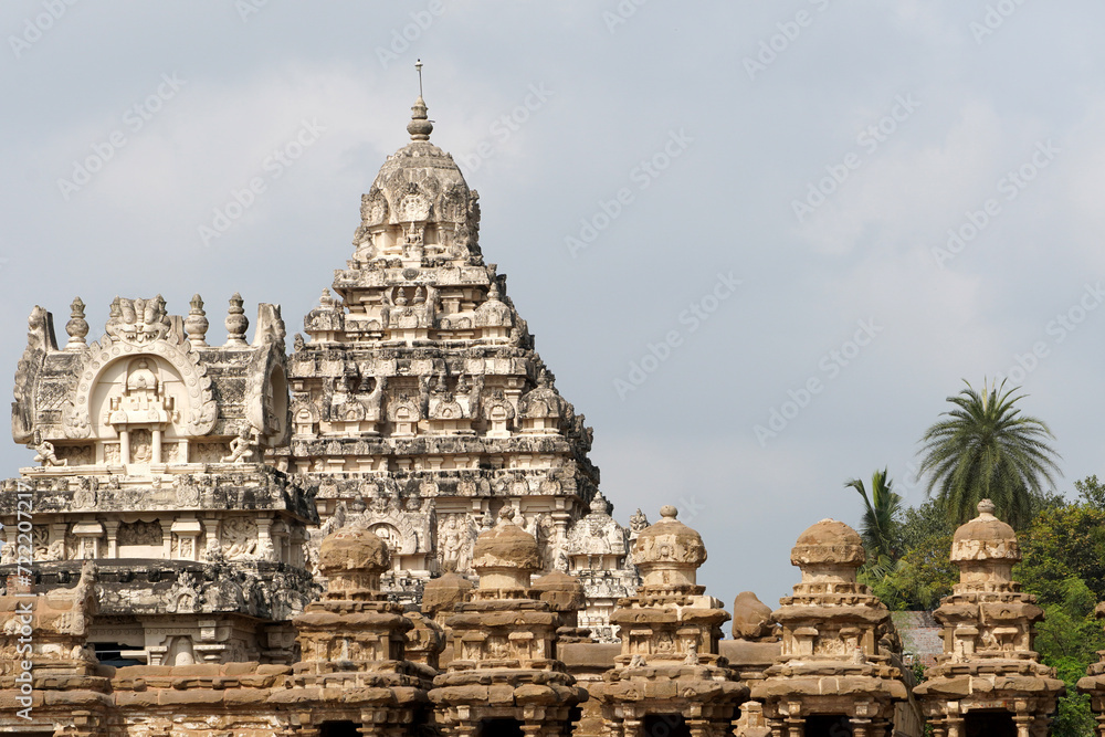 Facade of ancient Kailasanathar temple. Historic Hindu Temple tower with sandstone carvings against cloudy background.
