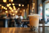 A cup with a straw of milk tea with boba bubbles on a table in a cafe. Banner for restaurant