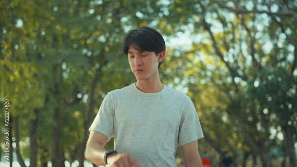 Asian man runner walking in public park and using smart watch for check the heartbeat, Portrait of fitness man checking result. Asian man runner walking in public park and using smart watch for check the heartbeat, Portrait of fitness man checking result.
