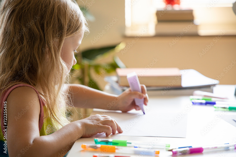 Little child girl draws while sitting at the table Little child girl draws while sitting at the table