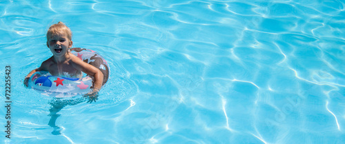   heerful child girl is played swimming with an inflatable ring in a summer pool. Banner