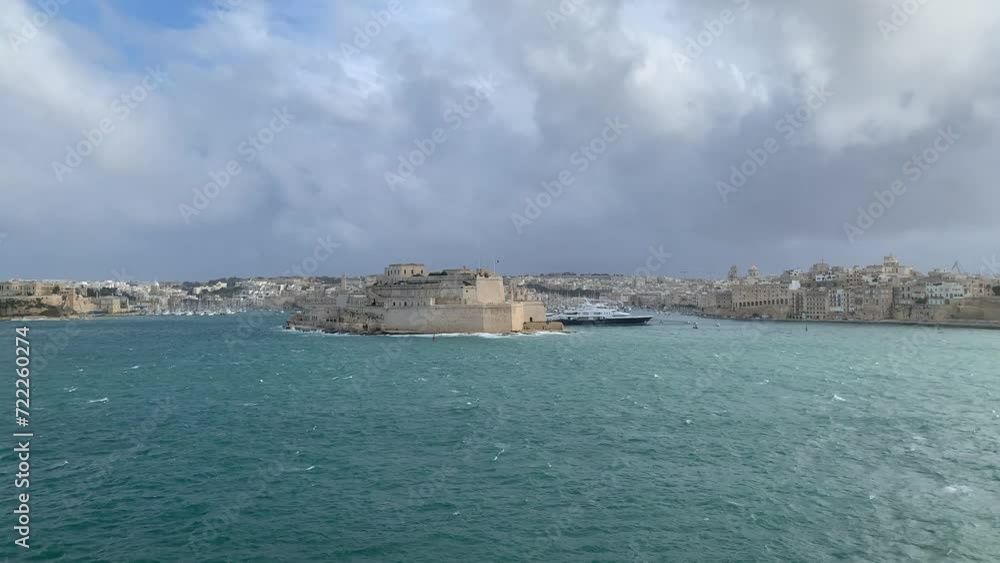 Panoramic view of three cities (Birgu (Vittoriosa), Bormla (Conspicua), Senglea) skyline with St. Angelo fort. Motion of heavy Mediterranean sea waves at Grand harbour. View from Valletta, Malta Panoramic view of three cities (Birgu (Vittoriosa), Bormla (Conspicua), Senglea) skyline with St. Angelo fort. Motion of heavy Mediterranean sea waves at Grand harbour. View from Valletta, Malta