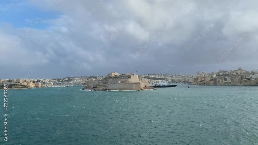 Panoramic view of three cities (Birgu (Vittoriosa), Bormla (Conspicua), Senglea) skyline with St. Angelo fort. Motion of heavy Mediterranean sea waves at Grand harbour. View from Valletta, Malta Panoramic view of three cities (Birgu (Vittoriosa), Bormla (Conspicua), Senglea) skyline with St. Angelo fort. Motion of heavy Mediterranean sea waves at Grand harbour. View from Valletta, Malta