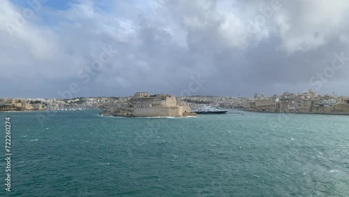 Panoramic view of three cities (Birgu (Vittoriosa), Bormla (Conspicua), Senglea) skyline with St. Angelo fort. Motion of heavy Mediterranean sea waves at Grand harbour. View from Valletta, Malta photo