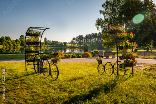 Decorative model of old bicycle equipped with baskets flowers against the backdrop of the lake .  Bicycles with baskets of flowers in the Smiltene Old Park, Latvia.