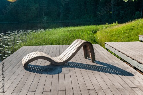 Sunbed on wooden terrace. Recreation area with sunbeds on the lake shore.