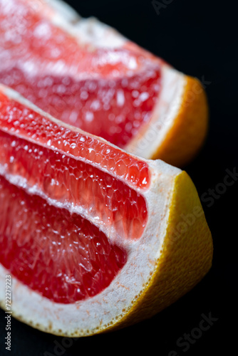 Two pieces of ripe grapefruit on a black background
