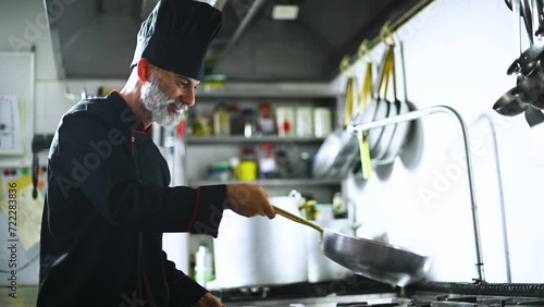 Mature chef jumping verdures in a pan photo