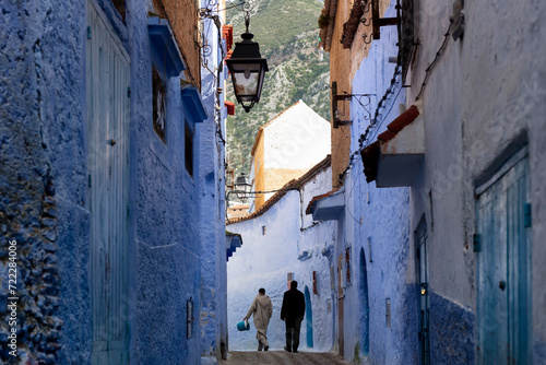 Men walking in an alley in Chefchaoeun, with the mountains in the background