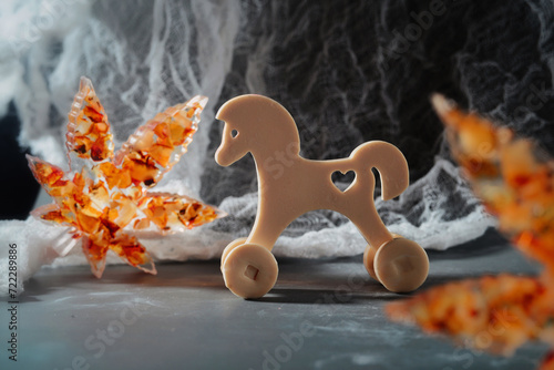 Wooden epoxy resin toy horse on a background of white lace. Copy space.