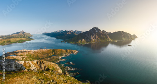 A panoramic view of the Lofoten archipelago under the midnight sun, with rugged peaks flanking the serene Nappstraumen strait