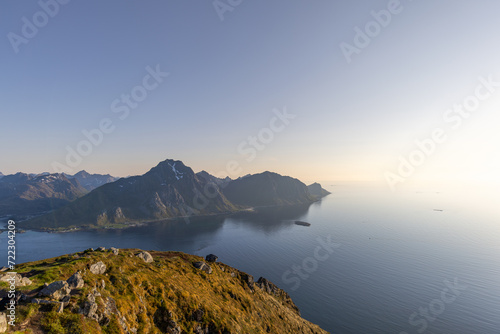 Soft light from the midnight sun bathes the rugged landscape of Offersoykammen, overlooking the tranquil Nappstraumen strait in the Lofoten archipelago