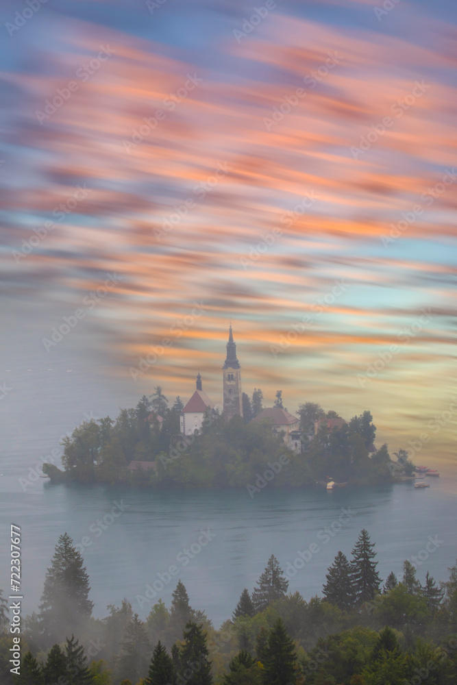 Famous alpine Bled lake (Blejsko jezero) in Slovenia, amazing autumn landscape. Scenic view of the lake, island with church, Bled castle, mountains and blue sky with clouds, outdoor travel background