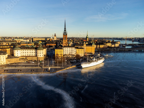 The old town of Stockholm in the winter sun, ice on the lake. Riddarholmen with its church and famous docked white boat. Medieval buildings, historic buildings. Blue sky