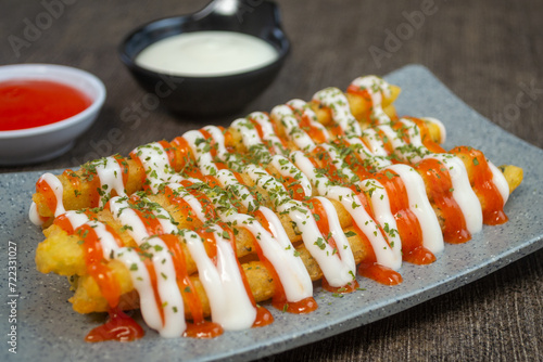 stik kentang keju or fried cheese potato sticks served with chili sauce, mayonnaise and a sprinkle of dried parsley photo