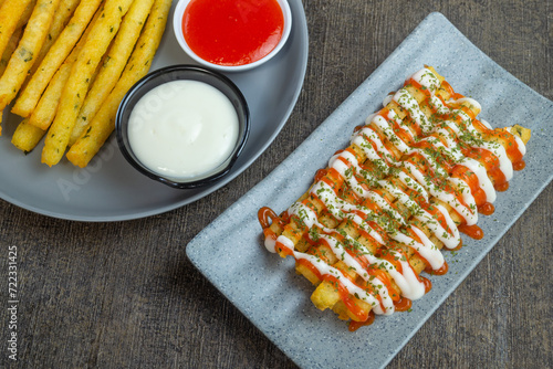 stik kentang keju or fried cheese potato sticks served with chili sauce, mayonnaise and a sprinkle of dried parsley photo