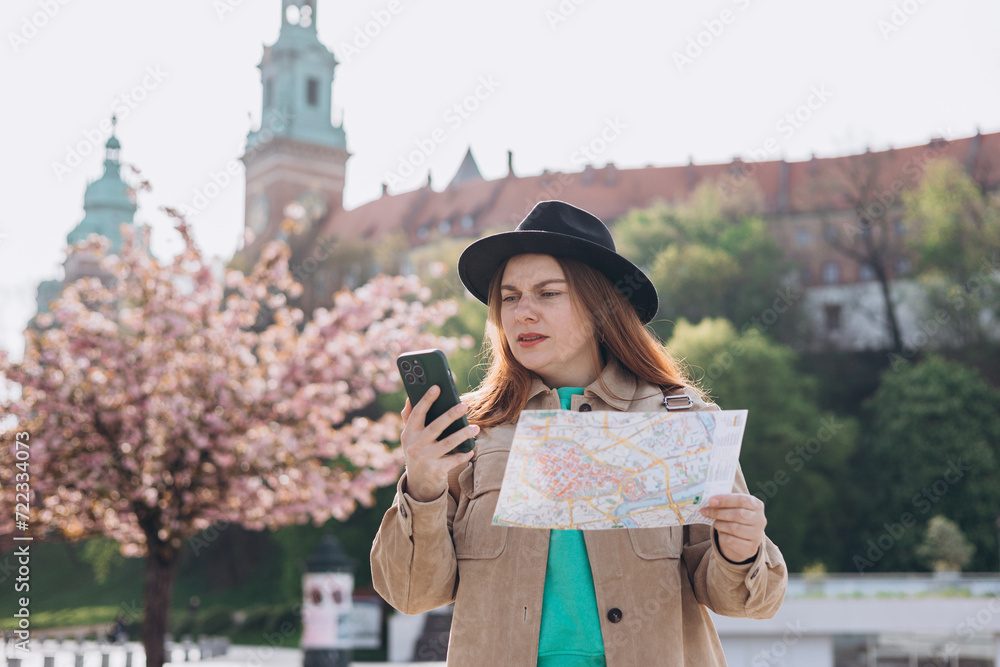 Negative people emotion. Upset young 30s woman with map is using a smartphone outdoors. Phone Communication. Urban lifestyle concept. Traveling Europe in spring. High quality photo