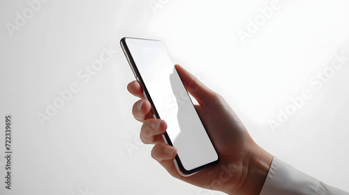 Hand holding an isolated smartphone device with blank empty white screen on white studio background, communication technology concept