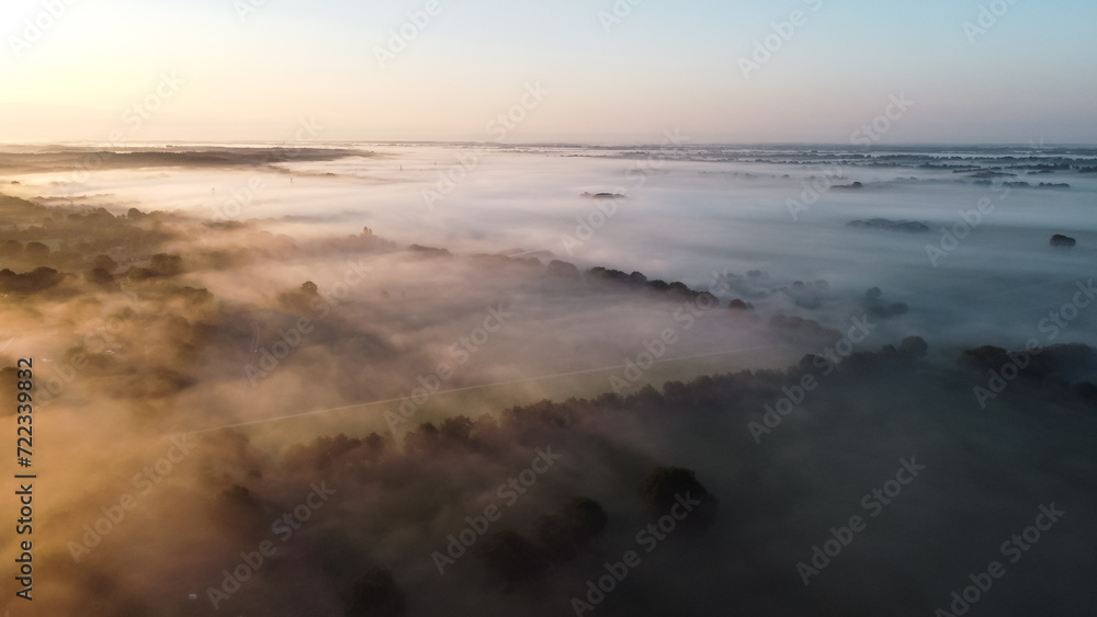 Aerial drone view of meadow landscape in The Netherlands on a sunny, foggy morning. Misty low clouds farmland landscape captured from above.