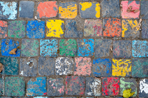 Photo of a vibrant street art piece featuring painted cobblestones in an array of colors, offering a playful twist on urban surfaces. photo