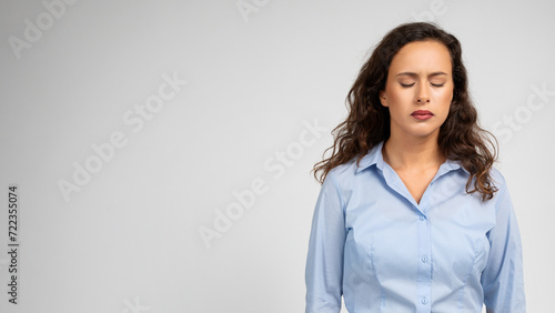 A contemplative young woman with closed eyes and curly hair photo