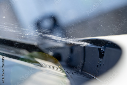 windshield washer system is sprayng the windshield washer fluid on the windshield close up, splashes