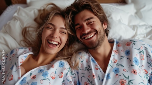A happy couple in matching pajamas laughs while lying in bed