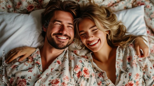 A happy couple in matching pajamas laughs while lying in bed