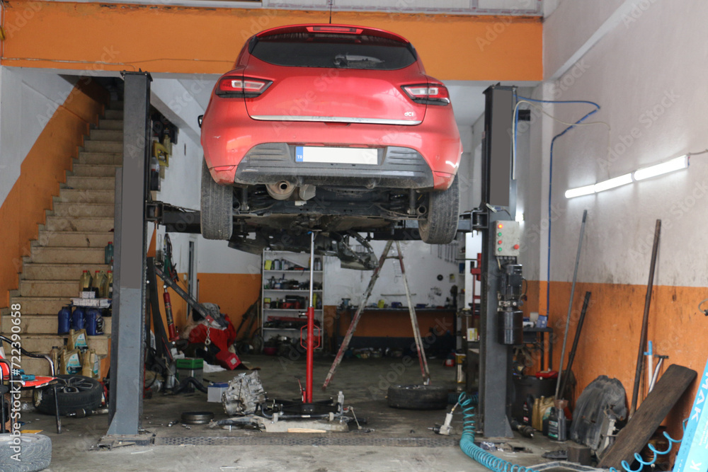 red car being lifted on a lift to repair the underside of the car